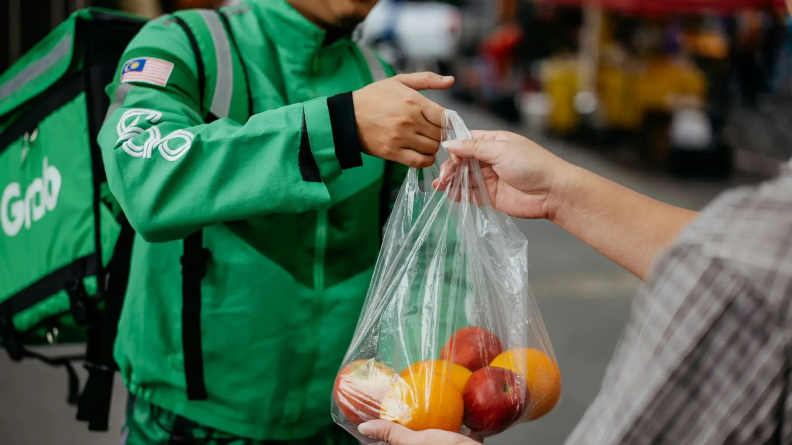 a man handing a bag of fruit to another man